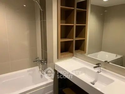 Modern bathroom with sleek fixtures and built-in shelving, featuring a bathtub and stylish vanity.
