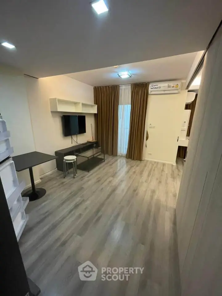 Modern living room with sleek flooring and wall-mounted TV in a cozy apartment.