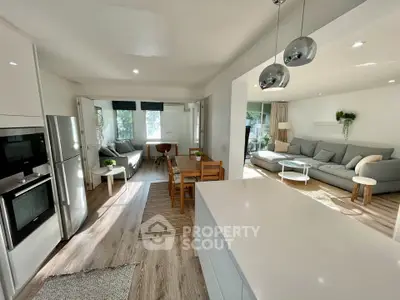 Spacious open-plan living room and kitchen with modern decor and natural light.