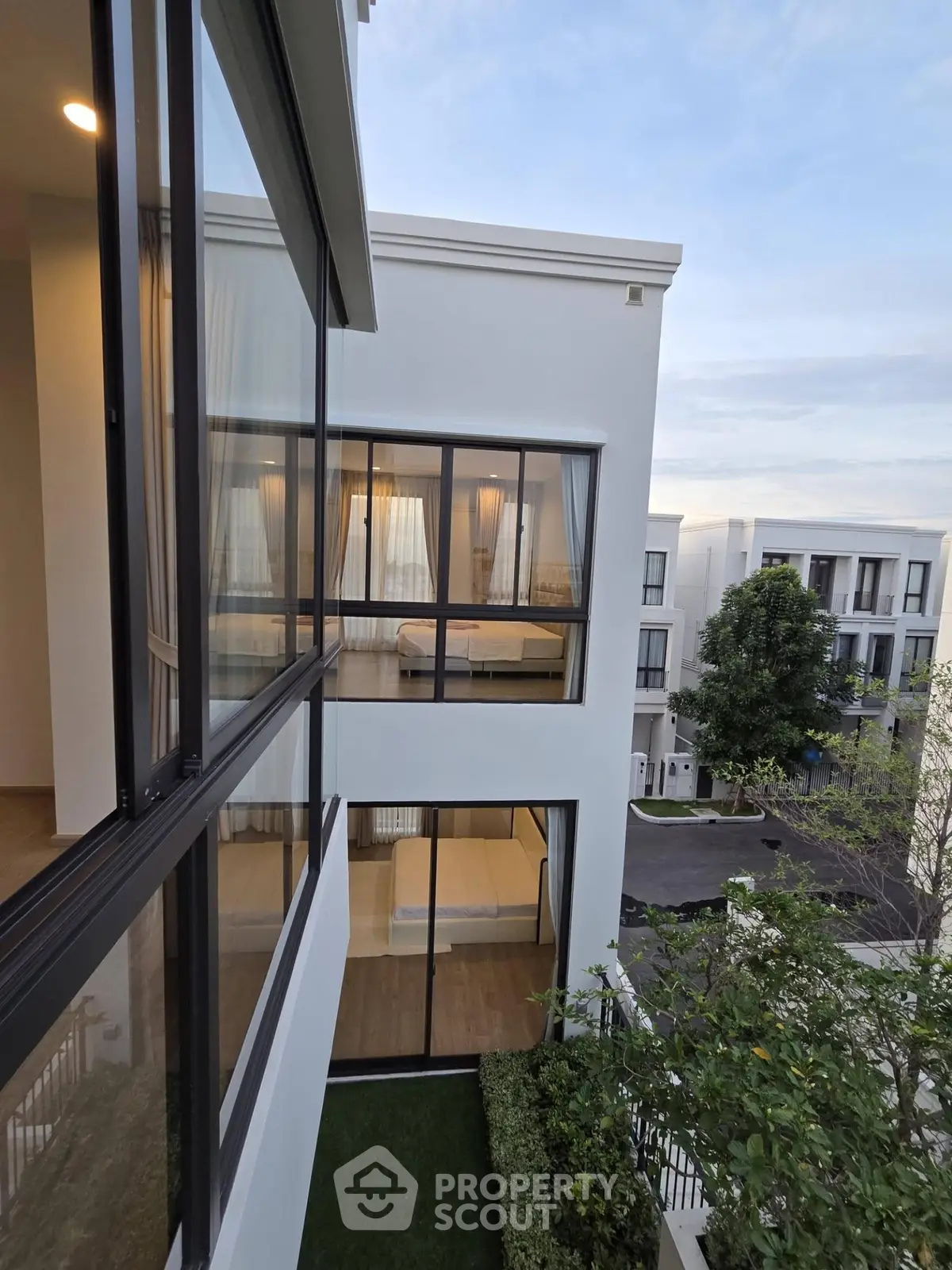Modern multi-story building with large windows and lush greenery, showcasing contemporary architecture.