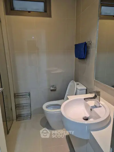 Modern bathroom with sleek fixtures and neutral tiles, featuring a stylish sink and toilet.