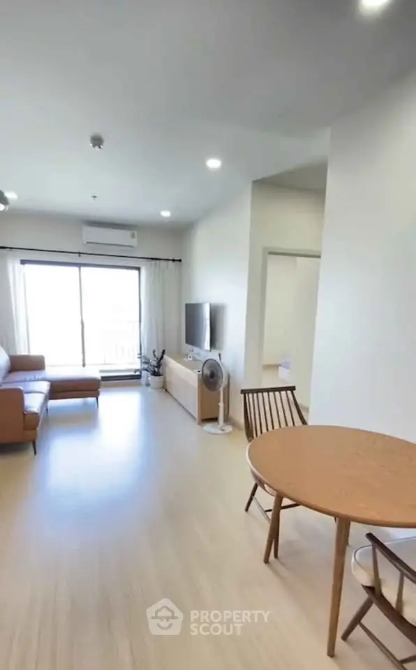 Modern living room with natural light, wooden flooring, and stylish furniture in a cozy apartment.