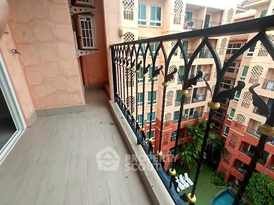Charming balcony with intricate railing overlooking a vibrant courtyard and pool in a stylish apartment complex.