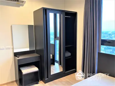 Modern bedroom with sleek black wardrobe and matching furniture, boasting natural light and a city view through large windows, ideal for urban living.