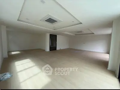 Spacious empty room with wooden flooring and modern ceiling design, ideal for customization.