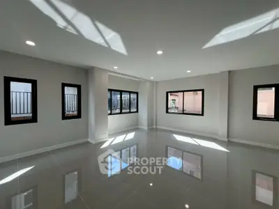 Spacious modern living room with large windows and glossy tiled floors, perfect for natural light lovers.