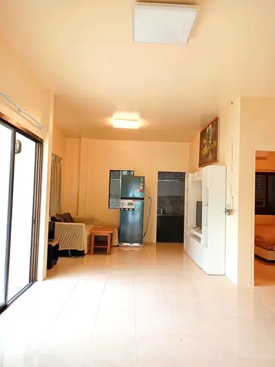 Spacious living room with modern decor and natural light, featuring a sleek refrigerator and cozy seating area.