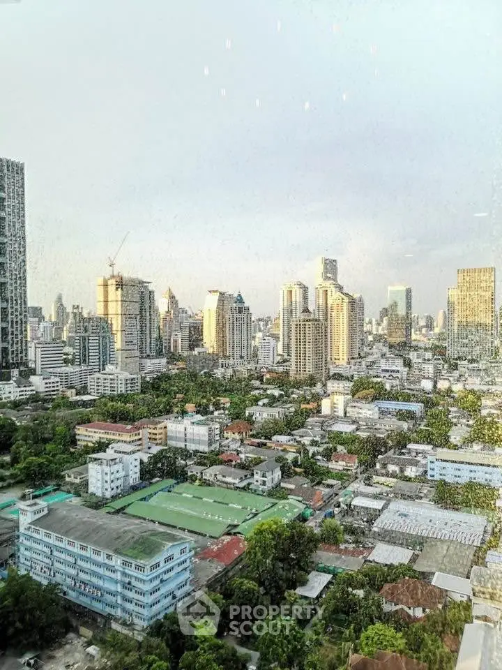 Stunning cityscape view from a high-rise building showcasing urban skyline and lush greenery.