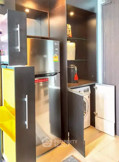 Modern kitchen with sleek storage, fridge, and built-in washing machine.
