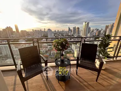 Stunning cityscape view from a high-rise balcony with cozy seating and lush greenery.