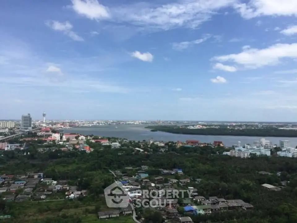 Stunning panoramic cityscape view with lush greenery and river under a clear blue sky.