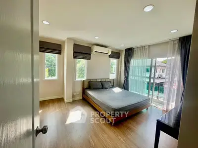 Spacious bedroom with large windows and balcony access in modern apartment