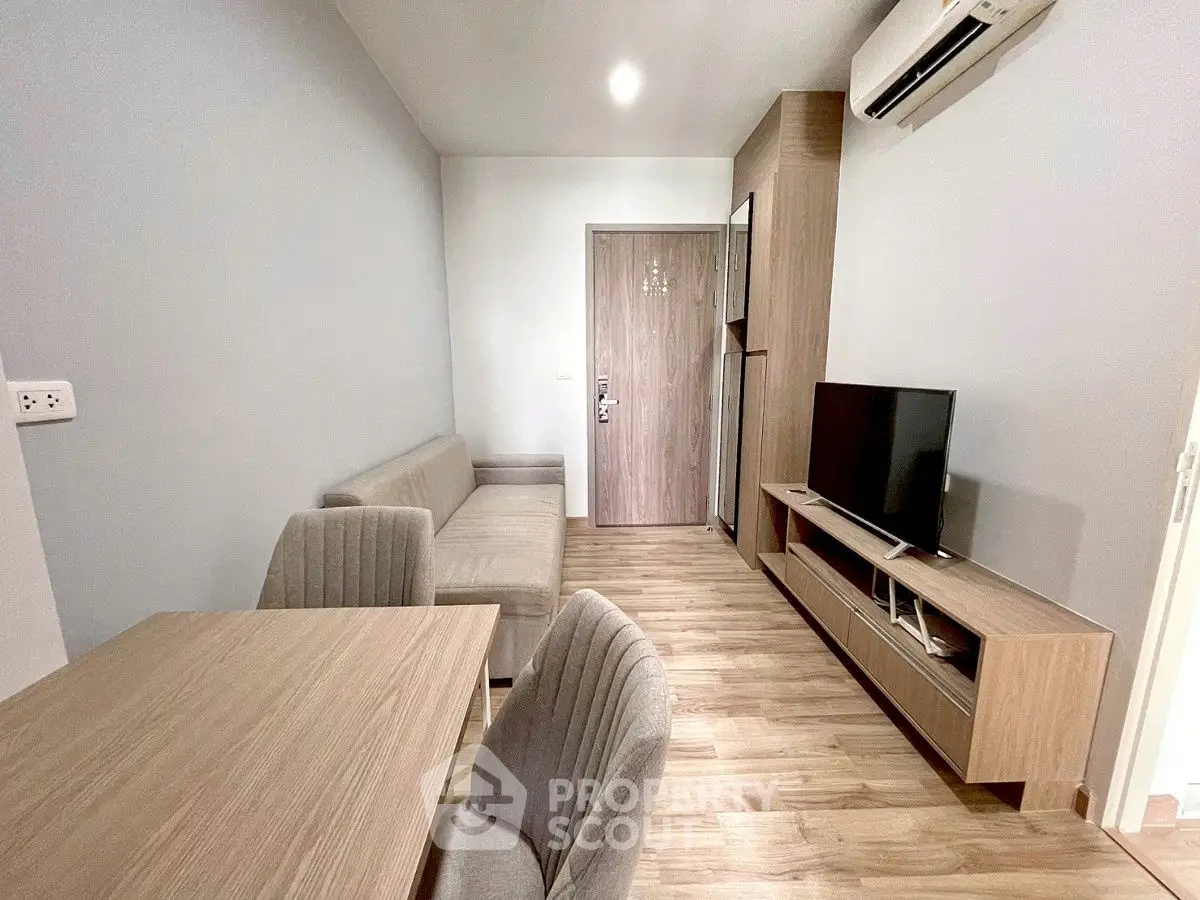 Modern living room with sleek furniture and wooden flooring, featuring a TV and air conditioning.