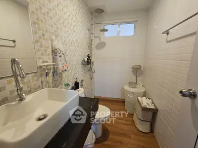 Modern bathroom with stylish sink and shower, featuring elegant tile design and wooden flooring.