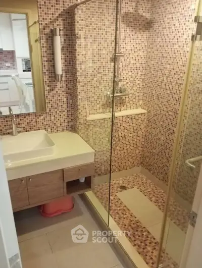 Modern bathroom with glass shower and mosaic tiles in stylish apartment.