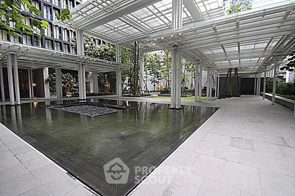 Modern architectural exterior with sleek water feature and lush greenery in a contemporary building courtyard.