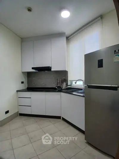 Modern kitchen with sleek cabinetry and stainless steel fridge in a compact layout.