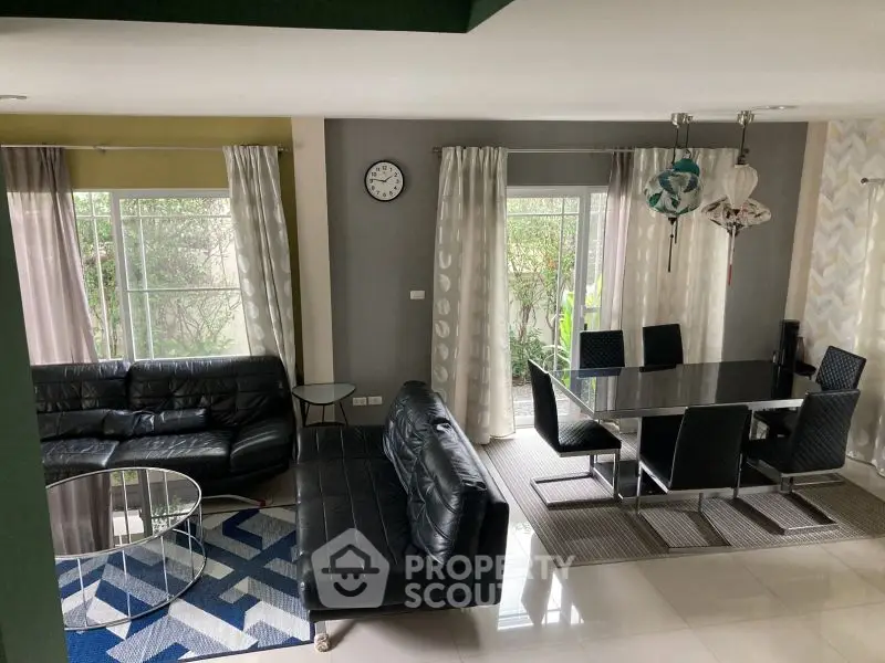 Modern living and dining area with sleek black furniture and large windows.