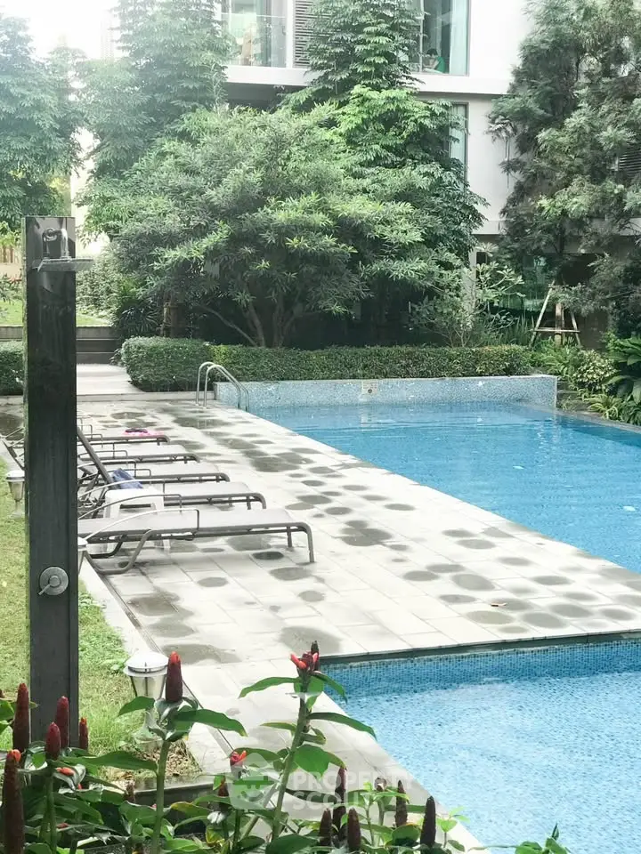 Luxurious residential pool area with lush greenery and modern design, perfect for relaxation and leisure.