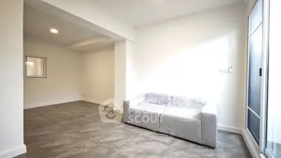 Spacious living room with modern gray sofa and ample natural light.