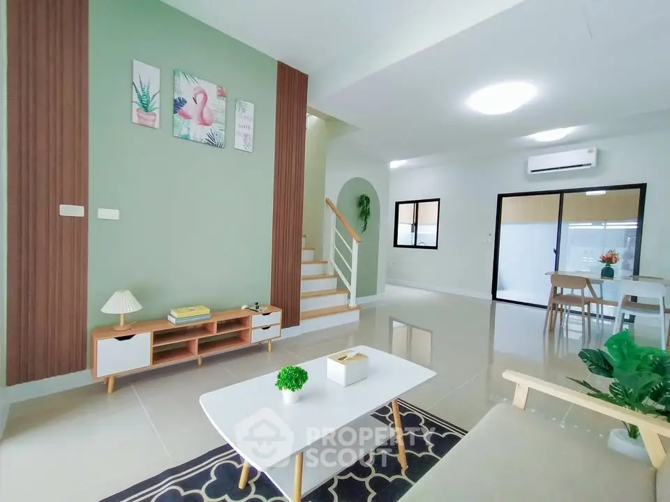 Modern living room with stylish decor and open layout, featuring a staircase and dining area.