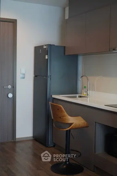 Modern kitchen with sleek cabinetry and stainless steel fridge in a stylish apartment.