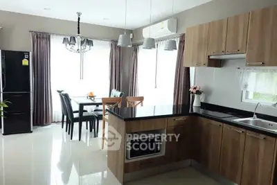 Modern kitchen with dining area, featuring sleek cabinetry and natural light.