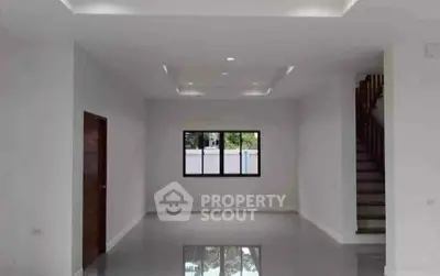 Spacious modern living room with sleek design and staircase, perfect for contemporary living.