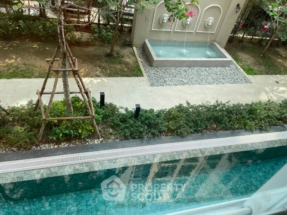 Luxurious poolside view with elegant garden and water feature in modern real estate setting.