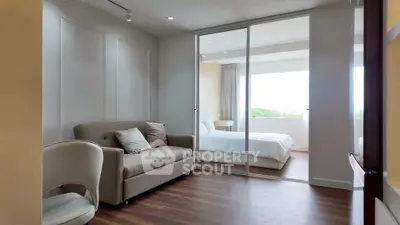 Modern bedroom with sliding glass doors and cozy seating area, featuring natural light and elegant decor.