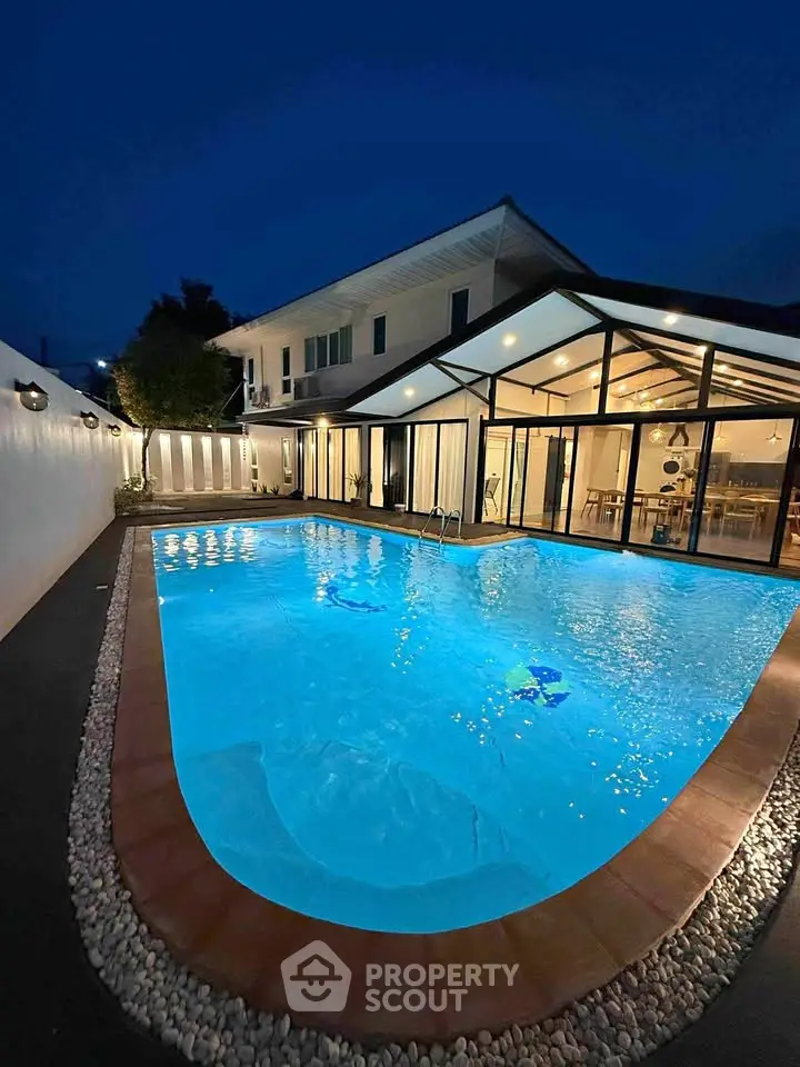 Luxurious villa with illuminated pool and modern glass extension at night
