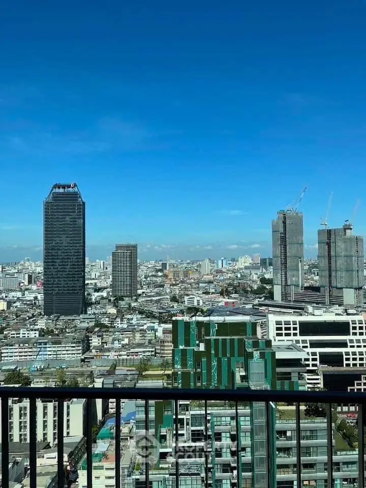 Stunning cityscape view from a high-rise balcony, showcasing urban skyline and clear blue skies.