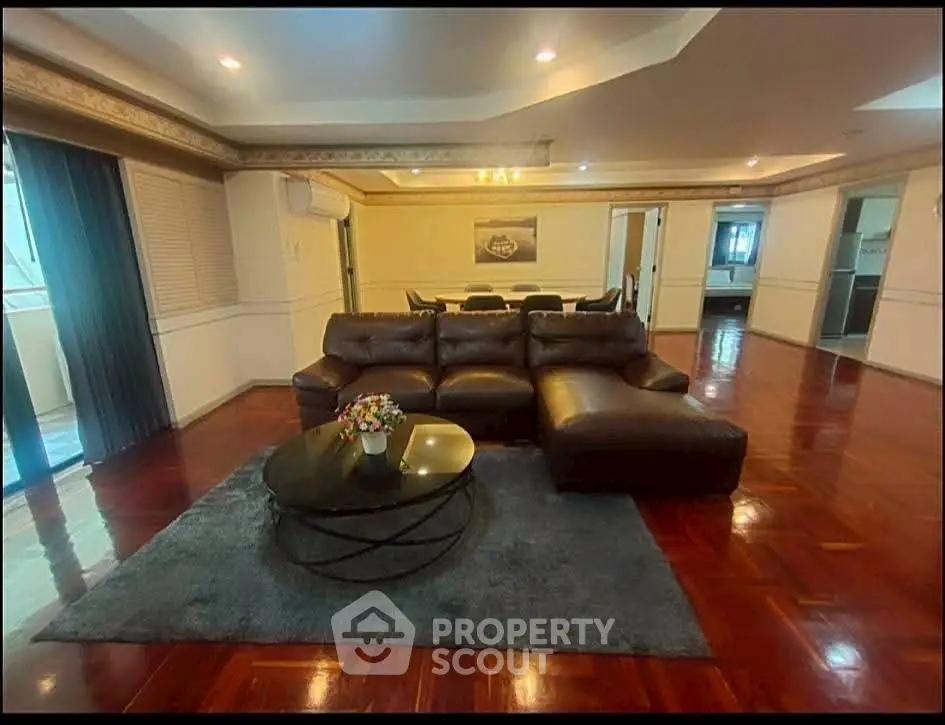 Spacious living room with elegant leather sofa and polished wooden floors in luxury apartment.