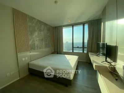 Modern bedroom with large window offering stunning city view and sleek furnishings.