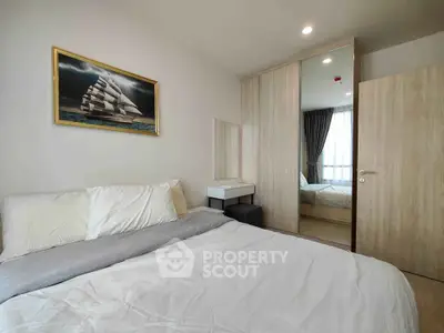 Modern bedroom with cozy bed, mirrored wardrobe, and nautical artwork, perfect for relaxation.