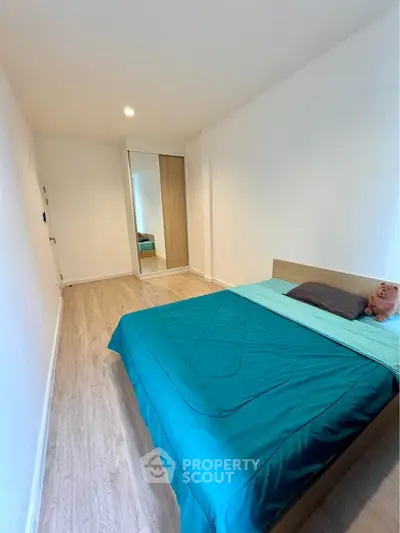 Spacious bedroom with modern decor and mirrored wardrobe, featuring elegant wooden flooring.