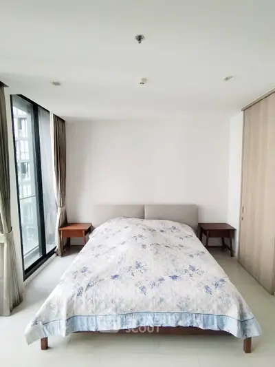Spacious bedroom with large windows and modern decor in a luxury apartment.