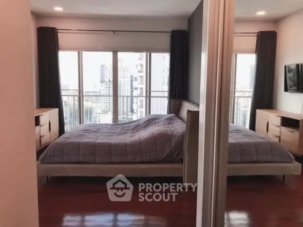 Spacious bedroom with large windows and city view, featuring modern decor and ample natural light.