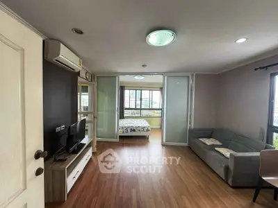 Spacious living room with modern decor and natural light, featuring a cozy sofa and entertainment unit.