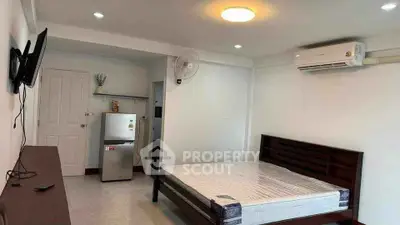 Modern studio apartment with bed, air conditioning, and compact kitchen area.