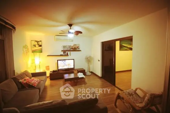 Cozy living room with modern decor and warm lighting, featuring a comfortable sofa and entertainment center.