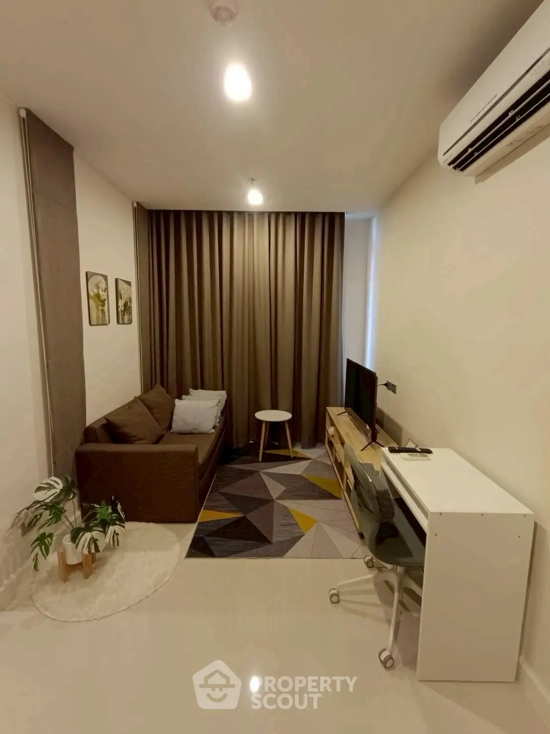 Modern living room with cozy sofa, stylish decor, and sleek air conditioning unit.