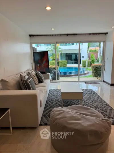 Spacious living room with pool view, modern decor, and cozy seating area.