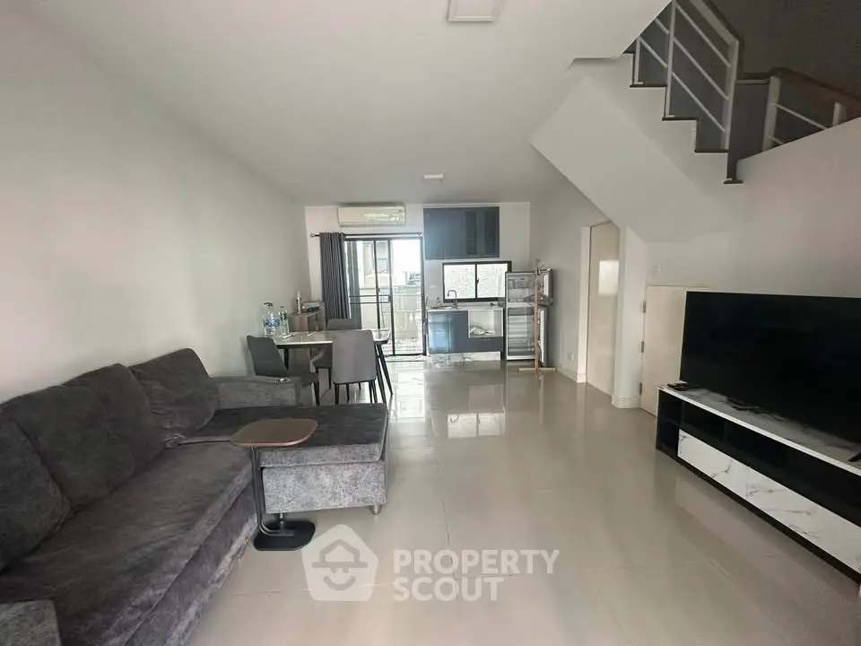Spacious modern living room with open kitchen and sleek staircase, perfect for contemporary living.