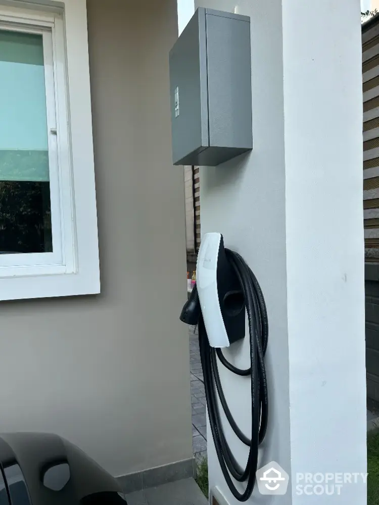 Modern home with eco-friendly electric vehicle charging station installed outside, showcasing sustainability and convenience for green living.