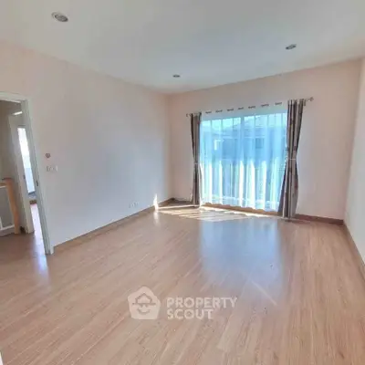Spacious empty room with large window and wooden flooring
