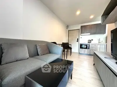 Modern living room with sleek furniture and open kitchen layout in a stylish apartment.