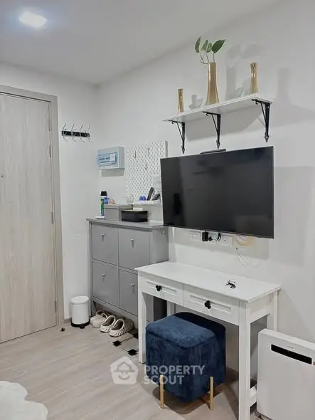 Modern living room with wall-mounted TV, stylish shelving, and sleek furniture in a cozy apartment.