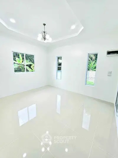 Bright and spacious living room with glossy tiled floors and modern chandelier.