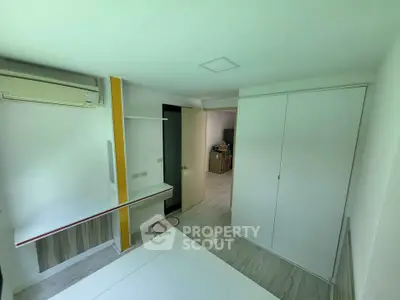Modern bedroom with built-in wardrobe and air conditioning in a minimalist design.